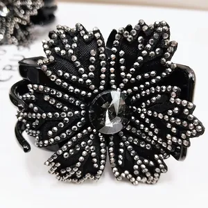 Detailed view of the sparkling rhinestone flower hair claw clip with black fabric petals