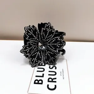 Detail shot of a black flower hair claw clip with rhinestones and a grey crystal center