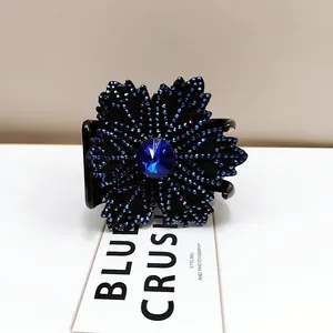 Detailed macro view of the rhinestone flower hair claw with faceted blue gemstone