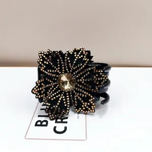 Detailed view of rhinestone flower hair claw clip with black petals and central crystal