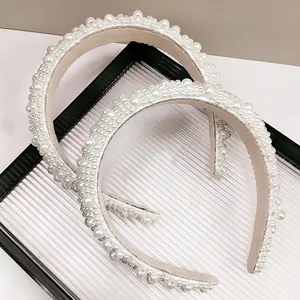 Détail de deux serre-têtes en perles blanches sur verre, mettant en valeur le style épais