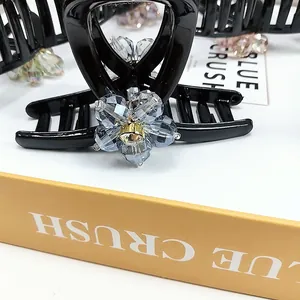 Detailed close-up of a large black hair claw clip with a sparkling crystal flower design