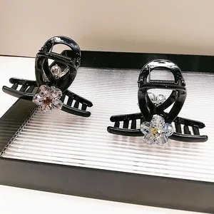 Elegant black hair claw clips with sparkling crystal flower accents in a luxury gift tray