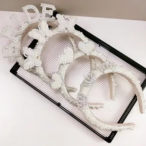 Detailed view of pearl bridal headbands with BRIDE lettering and butterfly motifs