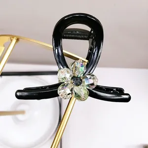 Detail of elegant black resin hair claw with crystal flower motif on a gold display