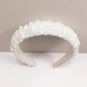 Détail du serre-tête baroque rembourré orné de perles blanches sur doublure beige