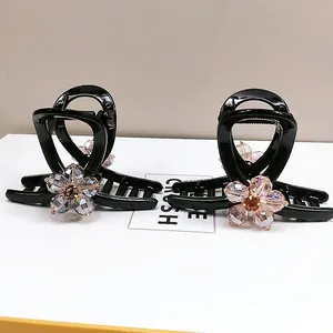 Detail view of two black resin hair claws with sparkling crystal flowers in pink and white