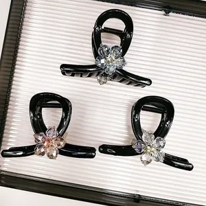 Close-up of three black hair claws with sparkling crystal flower designs on a tray