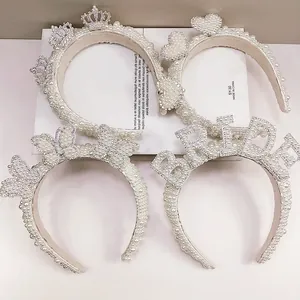 Detail of four white pearl bridal headbands featuring crown, heart, and bride lettering designs