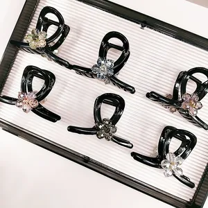 Set of six black hair claws with colorful crystal flower accents on a display tray
