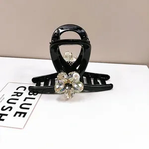 Detailed view of a black glossy hair claw featuring a sparkling crystal flower design