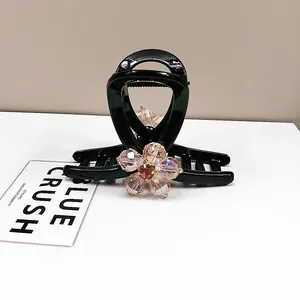 Detail of elegant black hair claw clip featuring champagne crystal floral petal ornaments