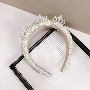 Detailed close-up of a white pearl headband featuring three rhinestone crown ornaments