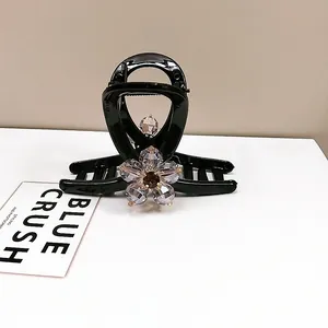 Close-up of black hair claw clip with sparkling crystal flower and elegant rhinestone inlay