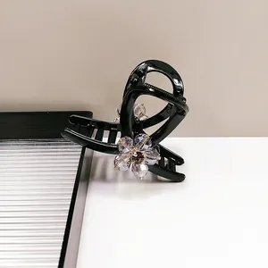 Detail of elegant black hair claw clip featuring transparent purple crystal flower accents