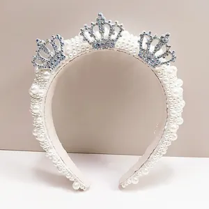 Detail of luxury pearl headband with three silver rhinestone crowns on soft fabric