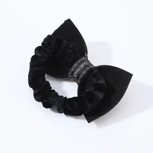Dettaglio di elastico nero per capelli con fiocco e nastro stampato 'HAND MADE' artigianale