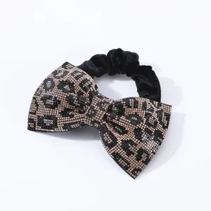 Dettaglio di un elastico per capelli a fiocco con strass motivo leopardato e velluto