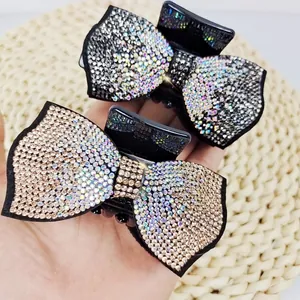 French bow hair claws with sparkling rhinestones in silver and gold, shown in hand
