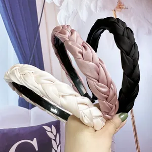 Détail des serre-têtes tressés en satin en couleurs crème, rose et noir