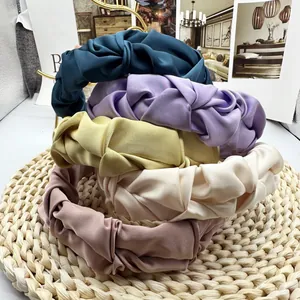 Detailed stack of five colorful satin pleated headbands with cross knot texture and sheen