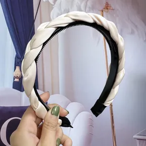 Détail du serre-tête tressé large en satin crème avec peigne intérieur noir antidérapant