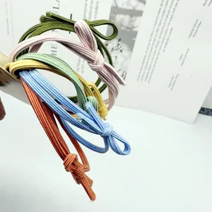 Close-up van vijf kleurrijke geknoopte elastische haarelastiekjes in snoepkleuren op blad