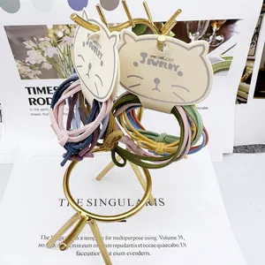 Detail van gevlochten haarelastiekjes in diverse kleuren op een gouden displaystandaard