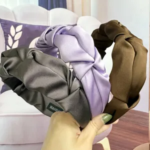 Detailed view of satin pleated headbands in dark grey, light purple, and deep brown colors