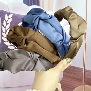 Detail shot of four pleated satin headbands in navy blue, brown, grey, and olive green