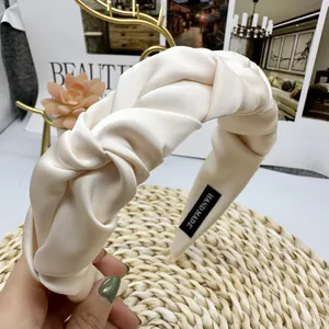 Detail of handmade cream satin pleated headband with premium twisted texture and hand-made label