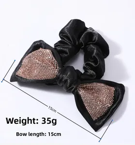 Detail view of 15cm oversized black satin bow scrunchie with champagne rhinestones