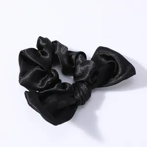 Dettaglio macro dell'elastico in raso nero lucido con fiocco e pieghe sottili ed eleganti