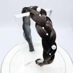 Détail d'un serre-tête tressé marron foncé orné de perles blanches de différentes tailles