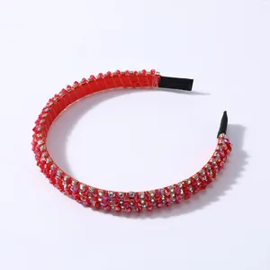 Detalle de diadema roja con cuentas de cristal y extremos protectores de tela