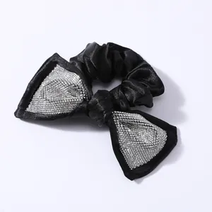 Dettaglio macro del fiocco di strass scintillanti su elastico scrunchie in raso nero
