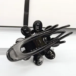 Close-up of the glossy black floral hair claw showing the sturdy metal duckbill clip