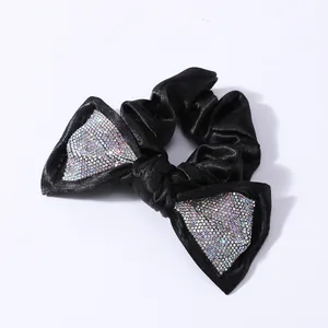 Dettaglio di scrunchie in raso nero con strass arcobaleno scintillanti sul fiocco
