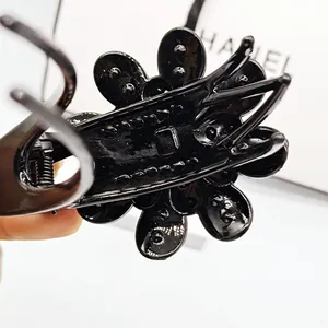Macro shot of the black floral hair claw clip featuring a glossy finish and metal spring