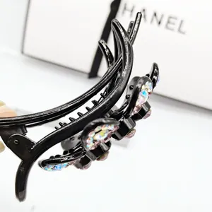 Detailed view of floral hair claw clip featuring colorful rhinestones on black glossy finish