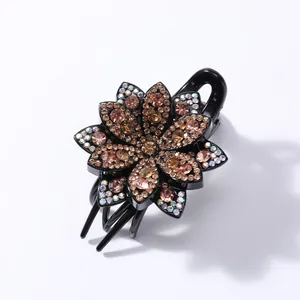 Macro shot of retro flower hair claw with amber rhinestones on a black glossy base