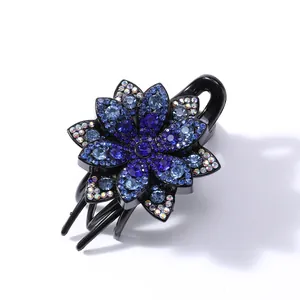 Detailed view of flower hair claw clip with blue rhinestones and black resin base