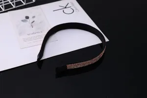 Gros plan d'un serre-tête noir mat serti de strass dorés sur une surface miroir