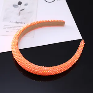 Detailed view of the bright orange padded headband covered in sparkling rhinestones