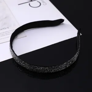 Gros plan sur un serre-tête fin en velours noir orné de strass étincelants et sombres