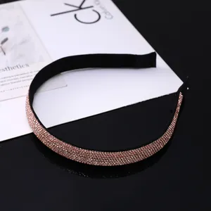 Détail d'un serre-tête fin orné de strass or rose sur une base en tissu noir