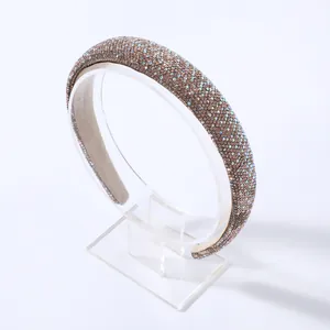 Dettaglio macro del cerchietto imbottito con strass iridescenti su tessuto marrone