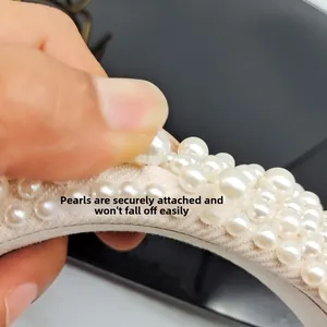 Detailed view of riveted white pearls on beige fabric headband showing durability