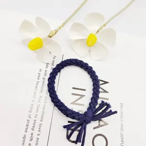 Nahaufnahme eines handgewebten, dunkelblauen Zopfgummis mit Quastenknoten und Blumen