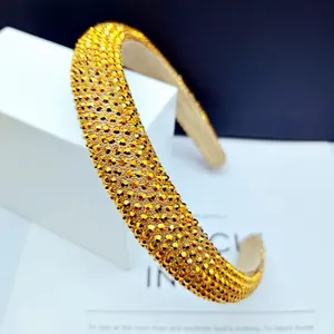 Detailed view of wide headband with yellow rhinestones on white geometric pedestal